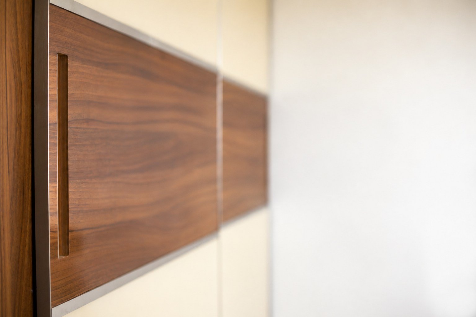 Close-up of a recessed vertical handle in wood-finish cabinetry.